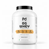 A white plastic tub of OG Whey protein powder with a black lid and a white label featuring black text and a small orange accent bar. The label reads OG WHEY and MALAI KULFI.